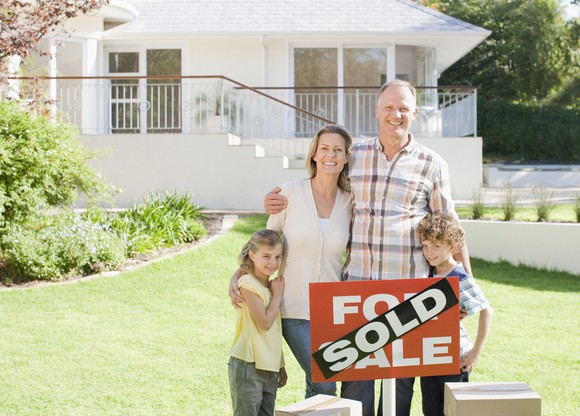 Family standing in front of a sold home.