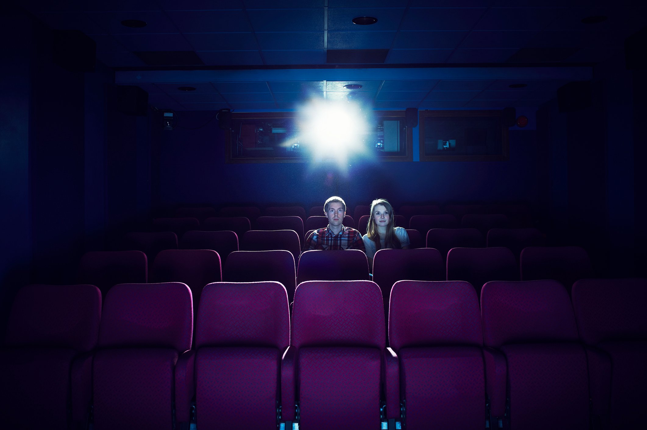Two people sitting in an empty movie theater.