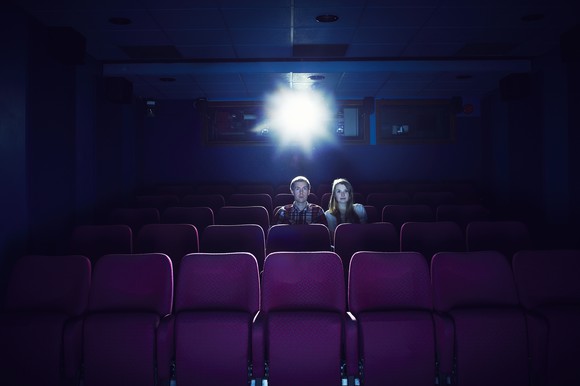 Two people sitting in an empty movie theater.