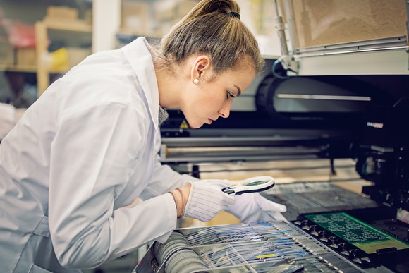 Person in lab coat examining semiconductor chips.