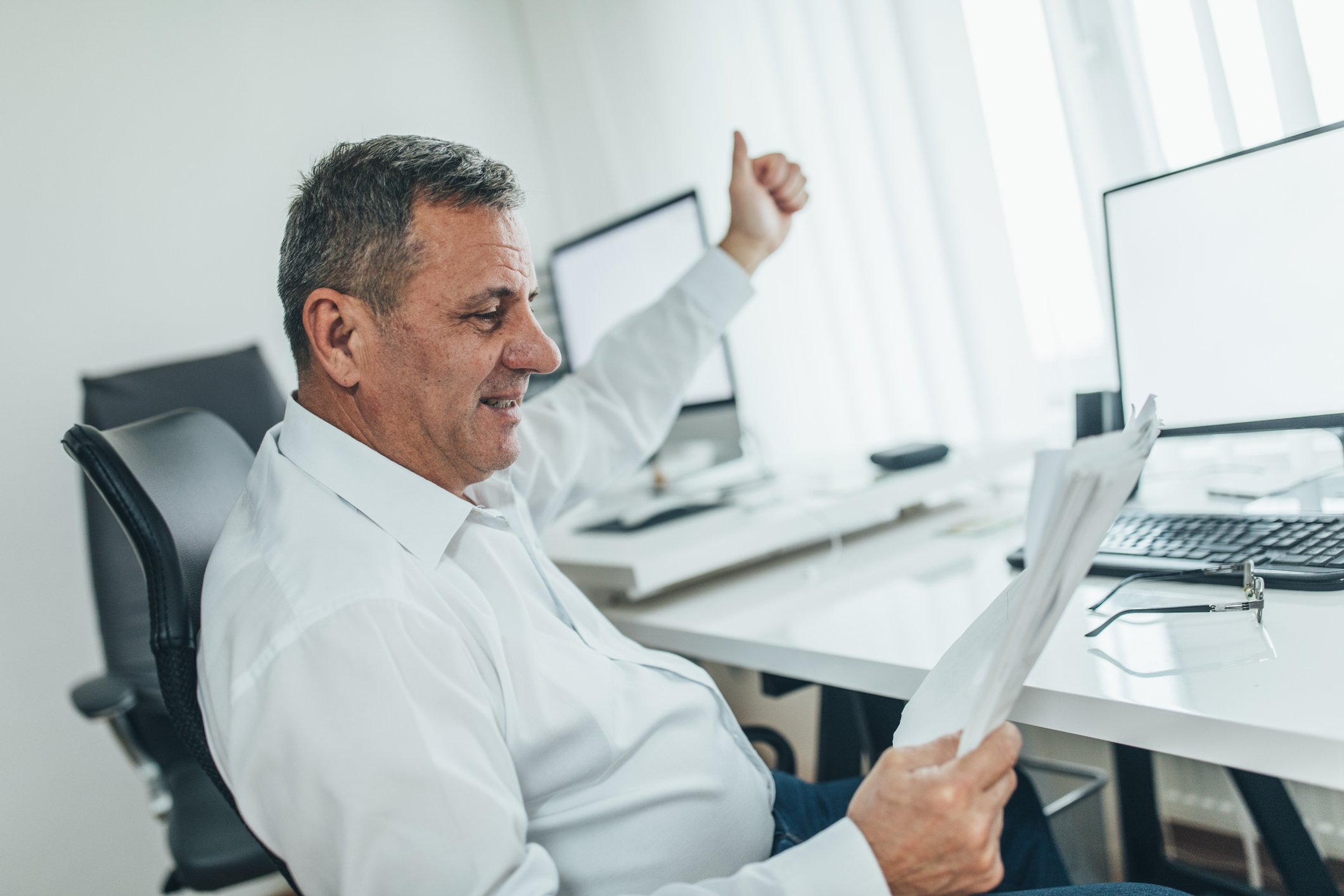 A person is giving a thumbs up sign while looking at documents. 