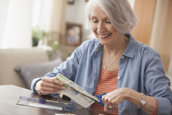A woman clipping coupons and smiling.