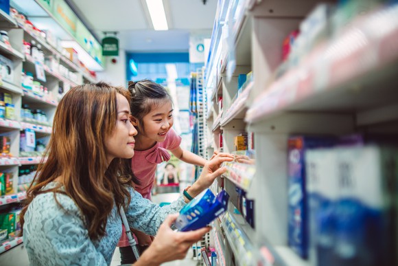 Adult and child looking at the shelves of a pharmacy.