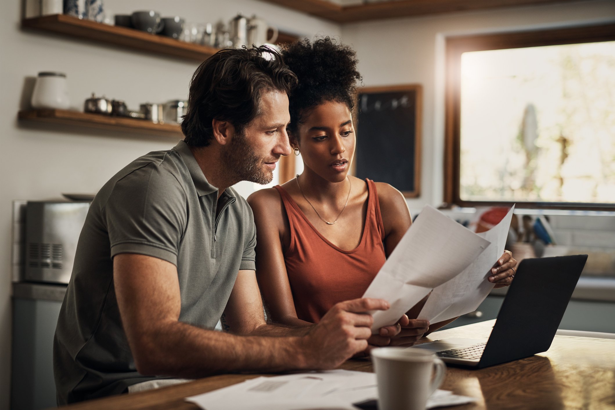 Two people looking at paperwork at kitchen table. 