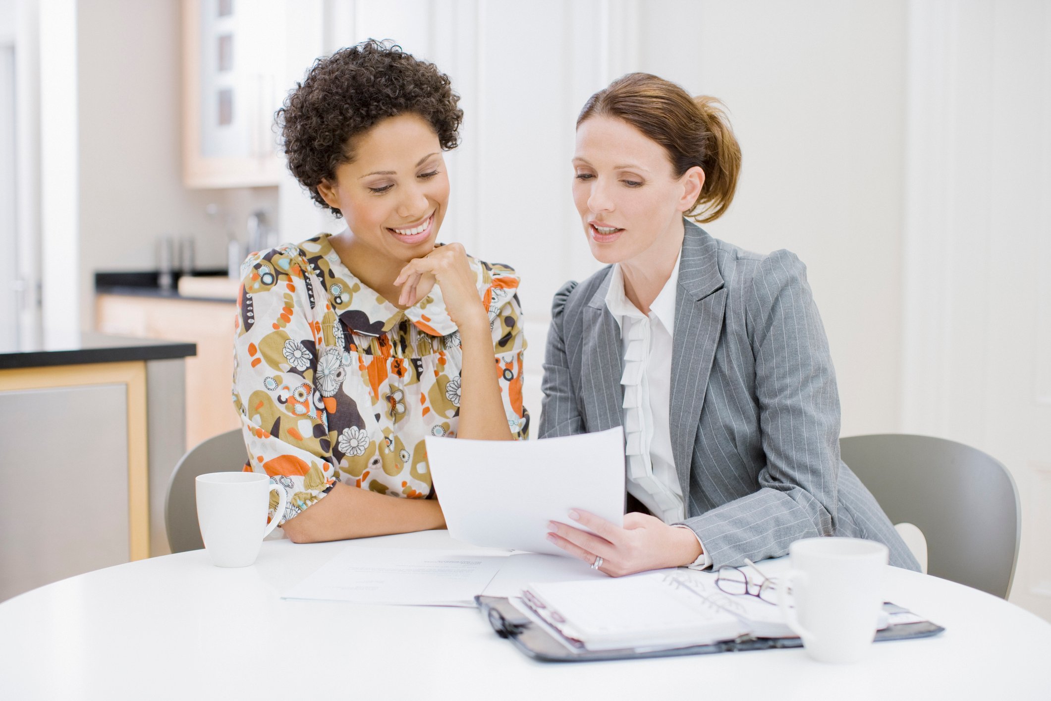 Two women going over information on a piece of paper.