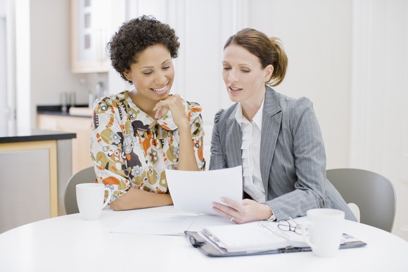 Two women going over information on a piece of paper.