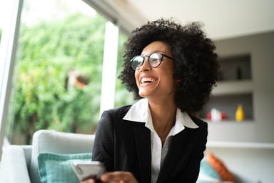 A happy businesswoman holds a smartphone.