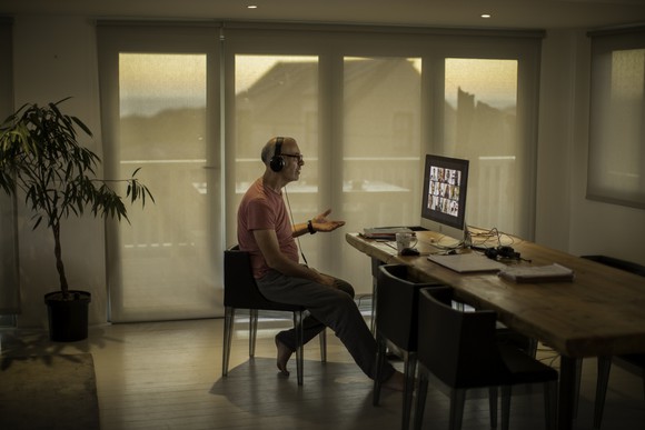 A remote worker wearing headphones while in a video conference from home.