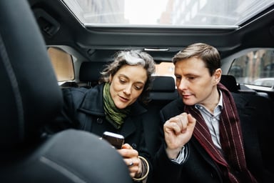 coworkers in back of car look at phone