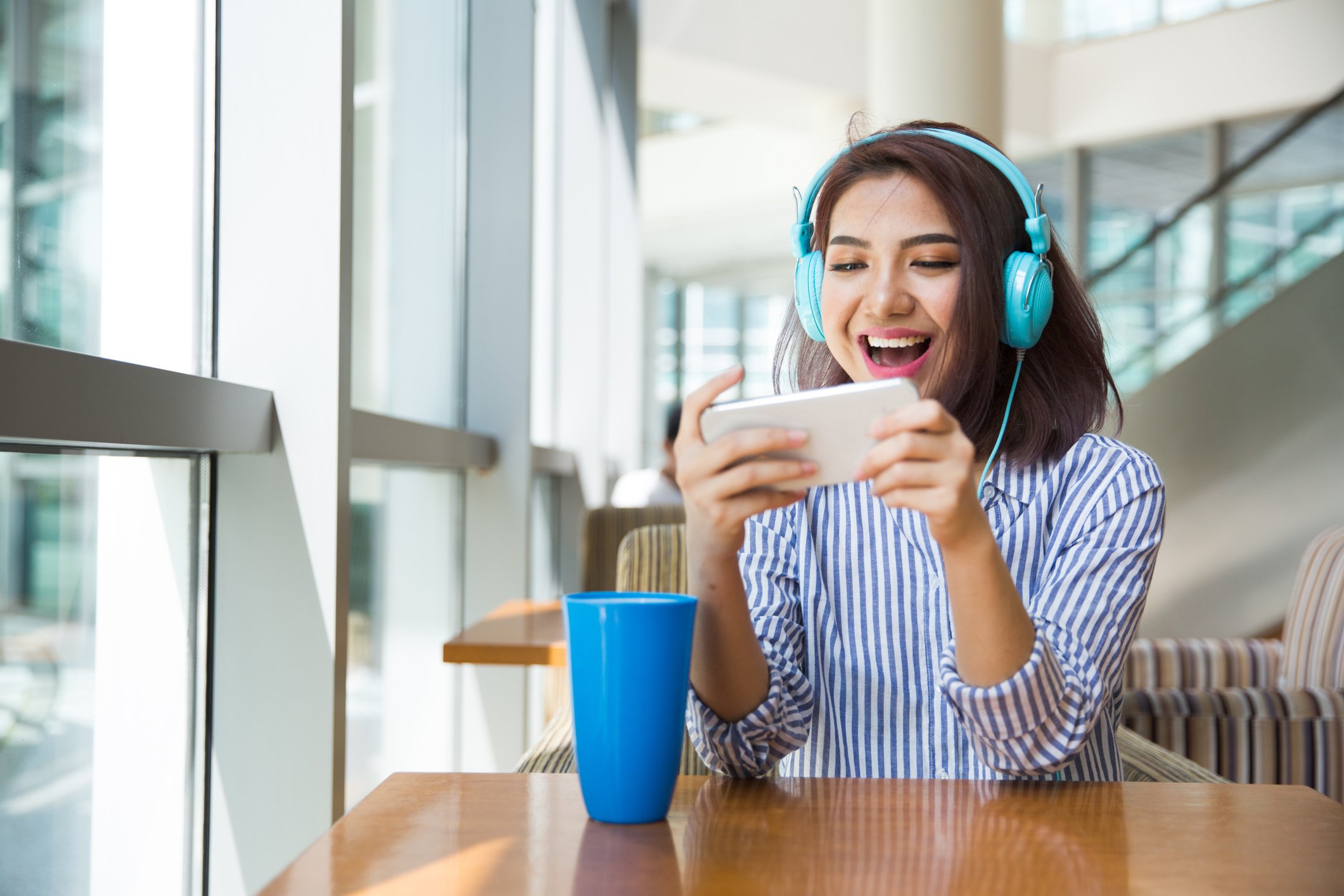 Person with headphones on playing a game on mobile phone.