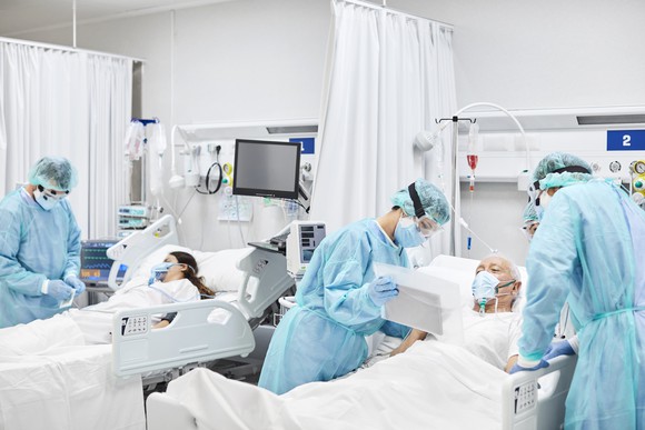 Healthcare professionals providing care to patients in hospital beds.