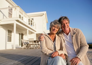 happy couple sitting on deck of beach house