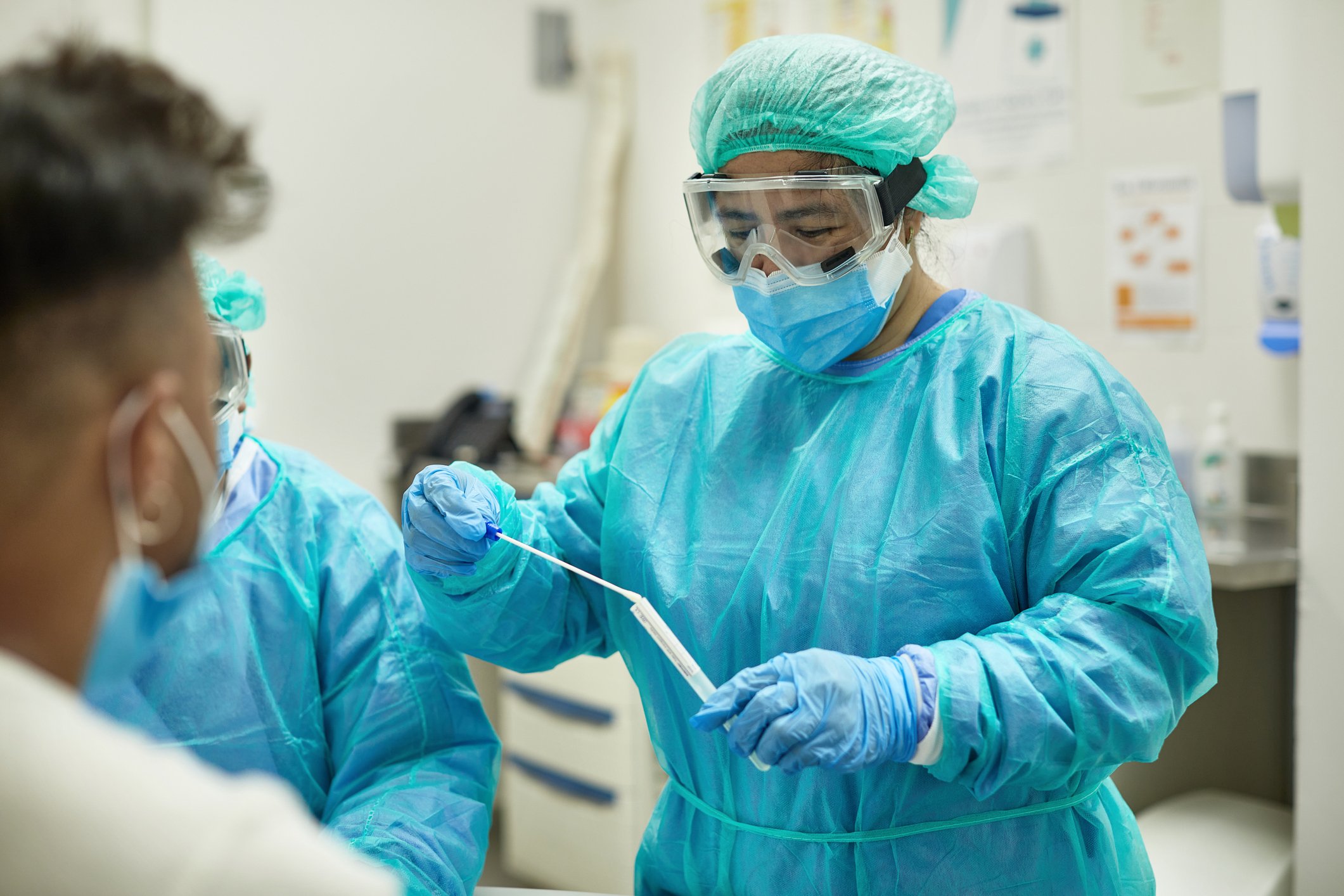 Medical professional putting a test swab in a container.