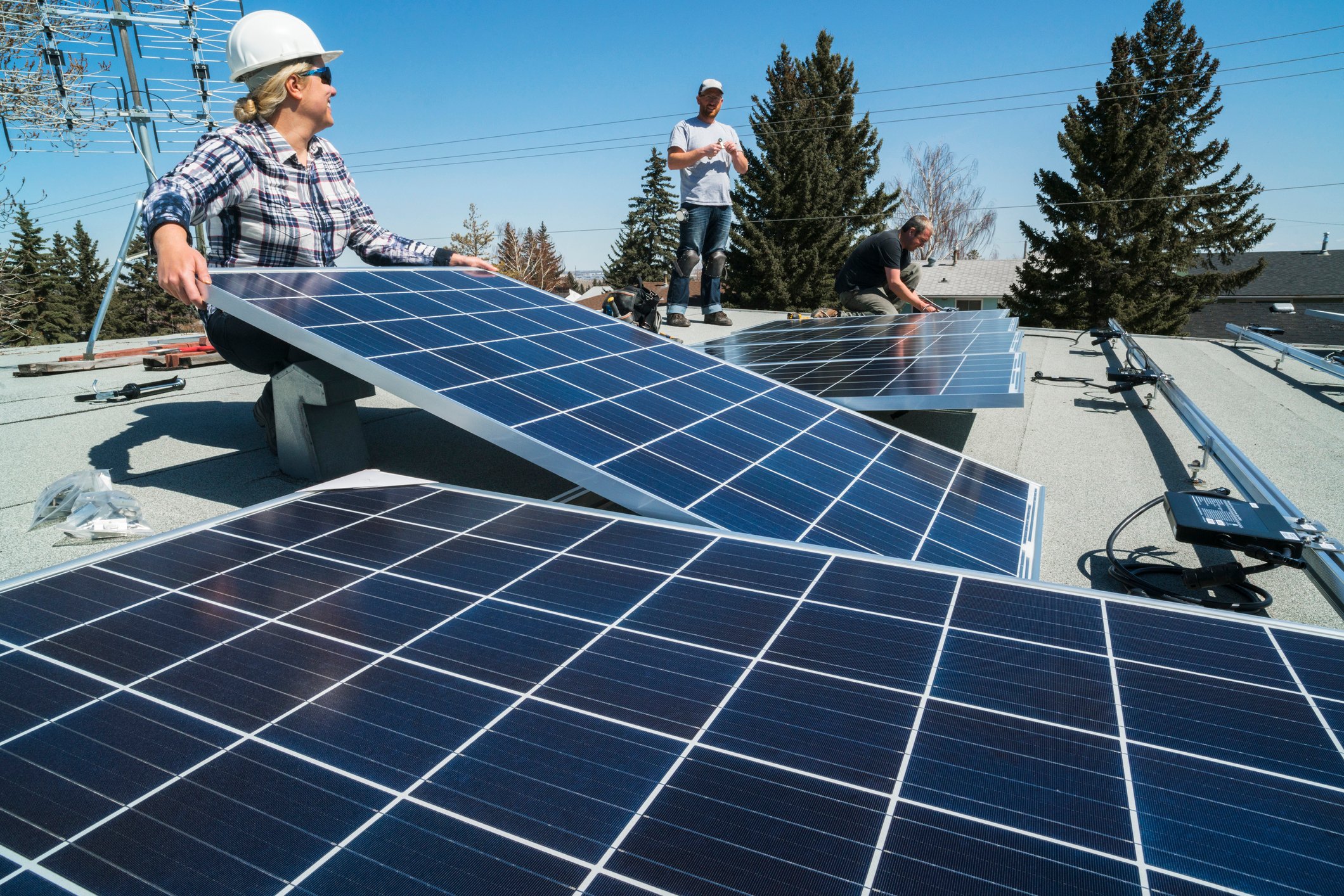 Workers install solar panels on a rooftop.