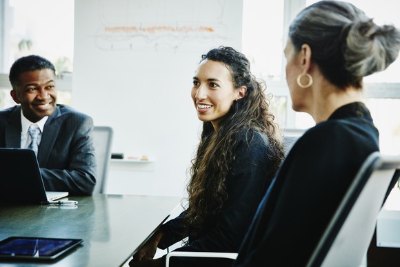 Three people in business attire seated in a conference room. 