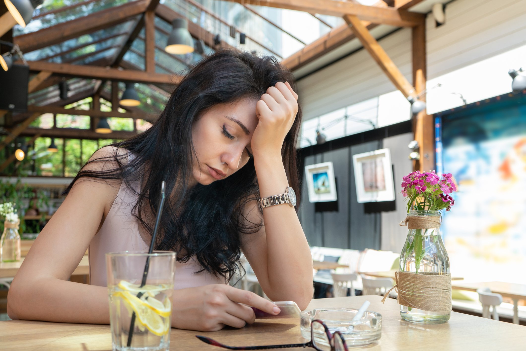 Sad woman with seltzer resting head on hand