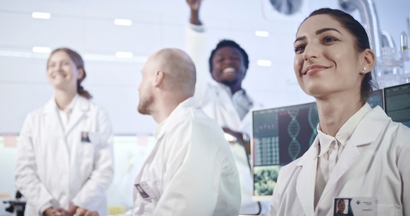 Four researchers smile in a laboratory setting.