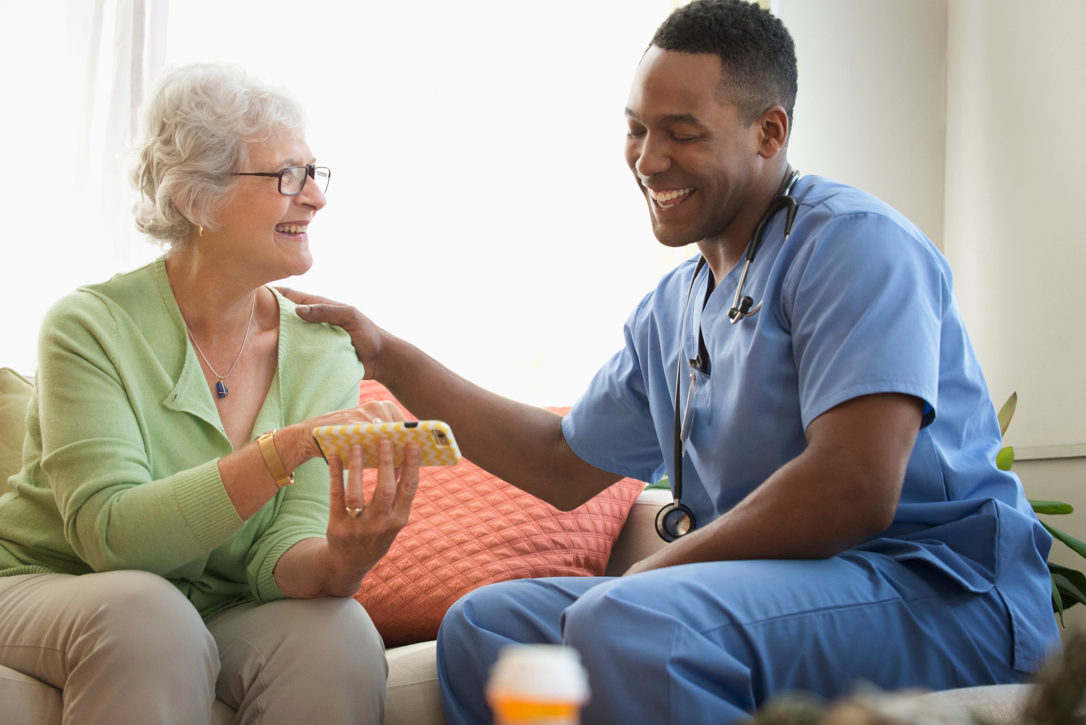 A home healthcare worker sits with a patient.