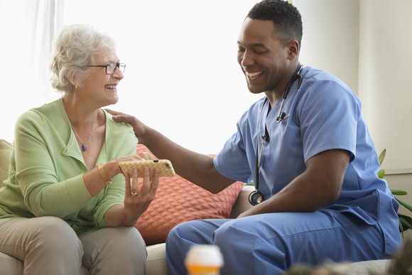 A home healthcare worker sits with a patient.