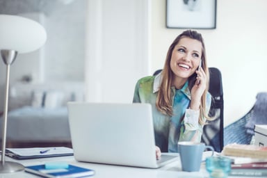 A person at a desk on a mobile phone.
