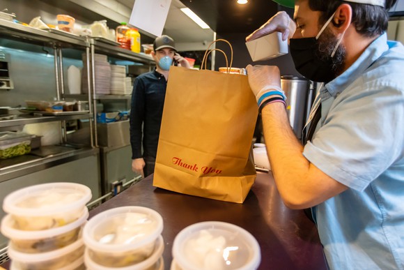 Restaurant worker preparing food for delivery driver. 