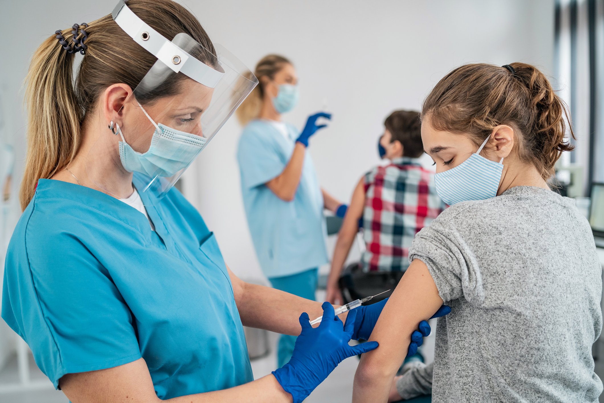 Healthcare worker giving vaccine to young person.
