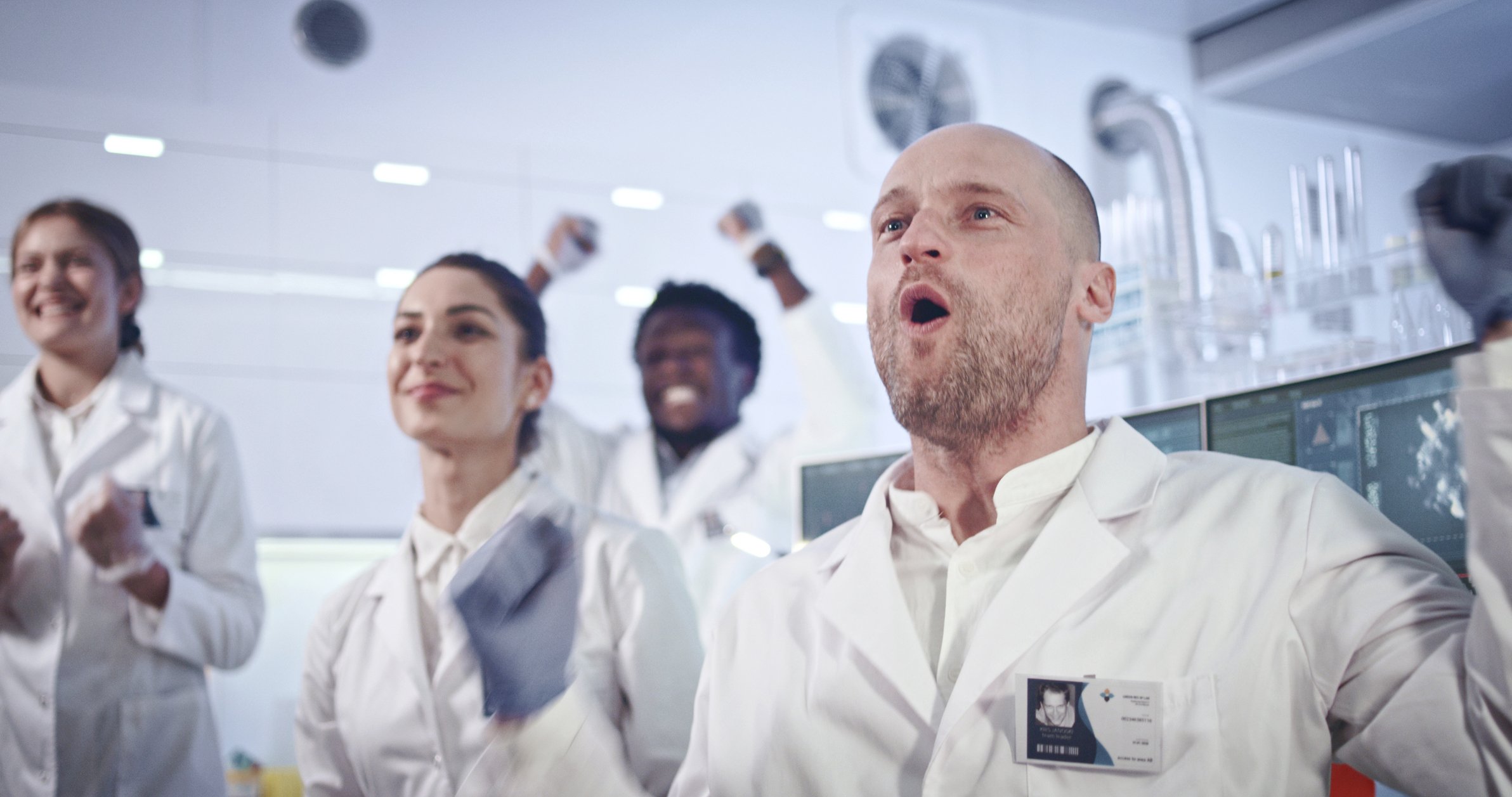 Scientists in white lab coats celebrating.