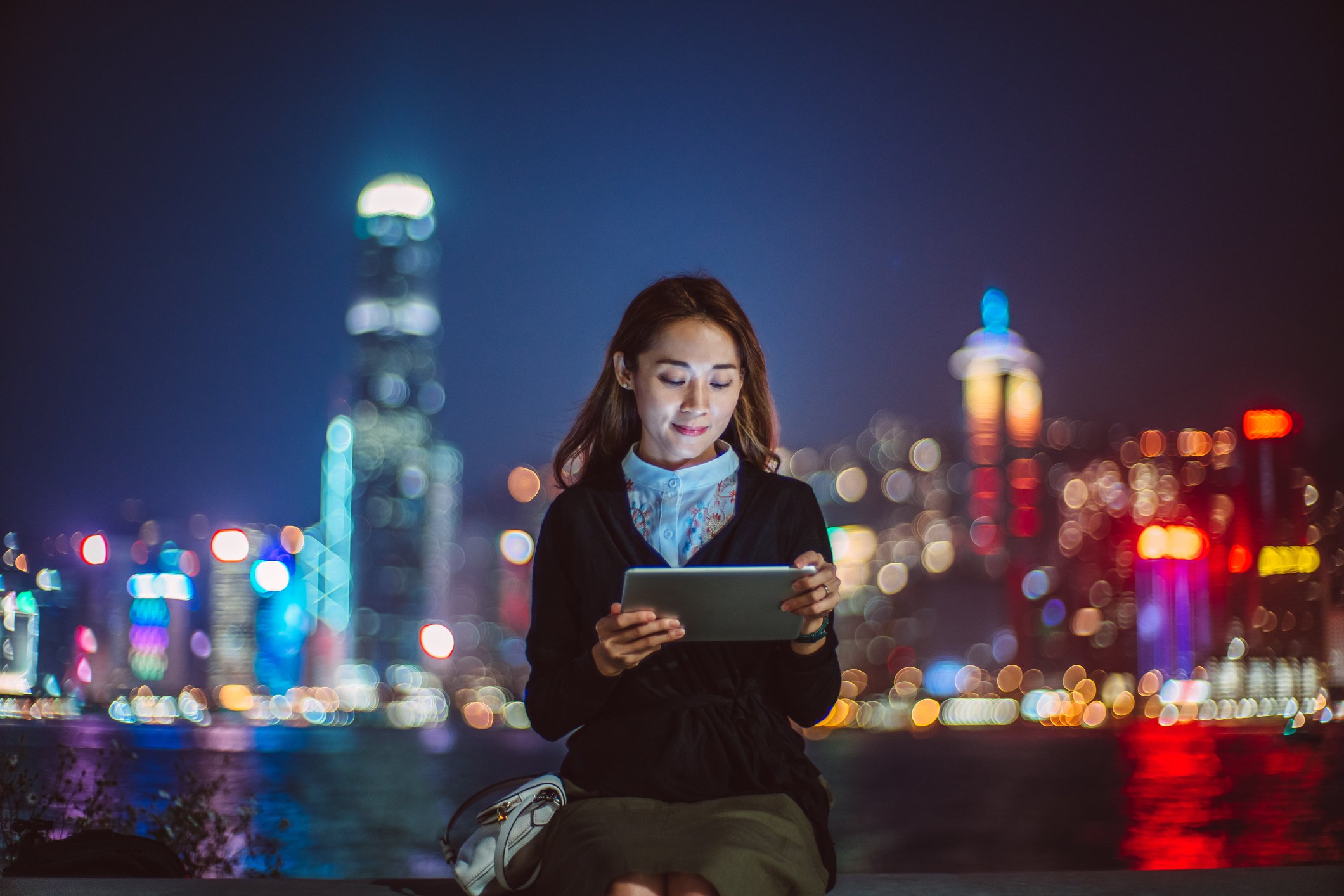 A tablet user with the Hong Kong skyline in the background.