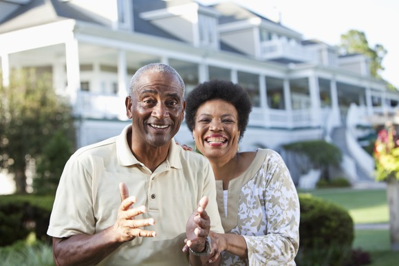 A couple standing in front of a large house.