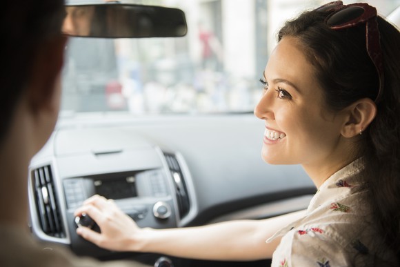 A passenger turns the knob on a car radio.