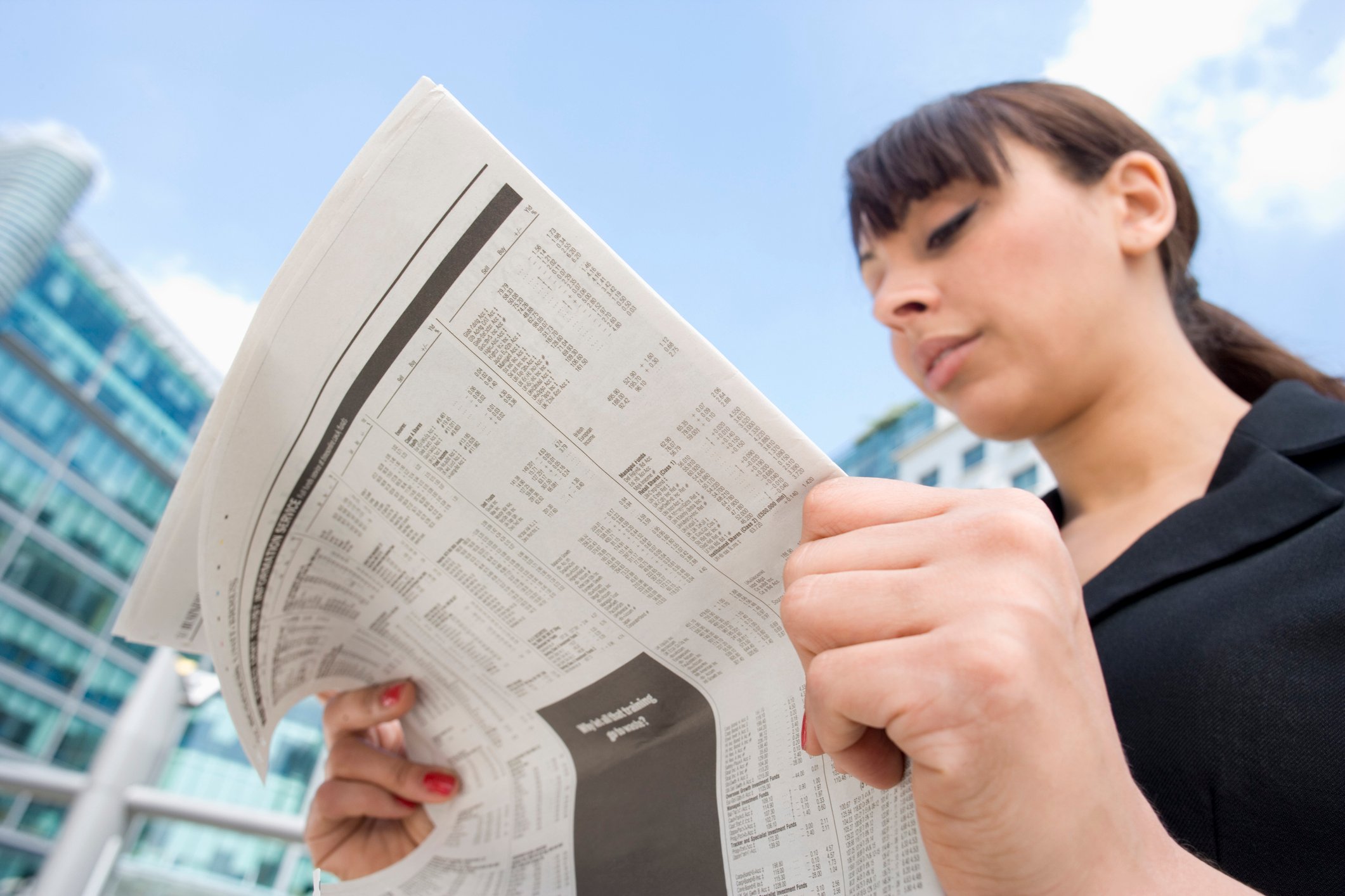 A woman reads a newspaper.