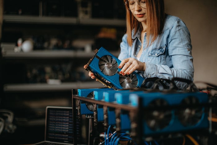 Woman holding machine in room with lots of other hardware.