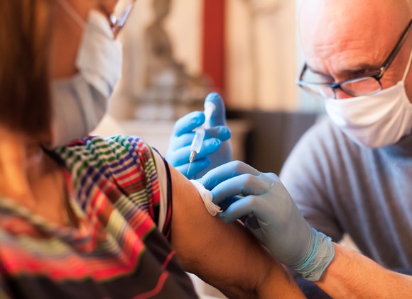 A doctor vaccinates a patient in her home.