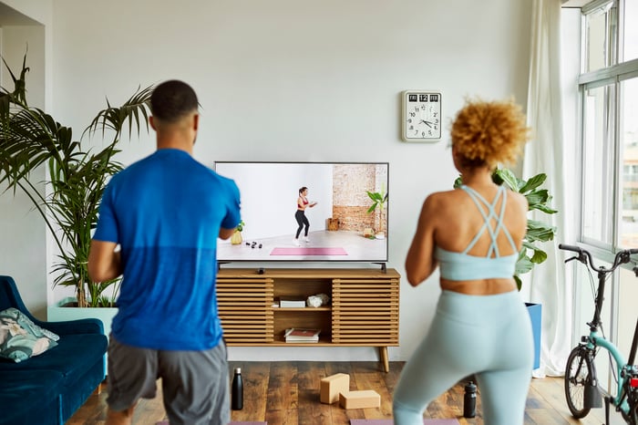 A couple works out as they stream an exercise video in their living room.
