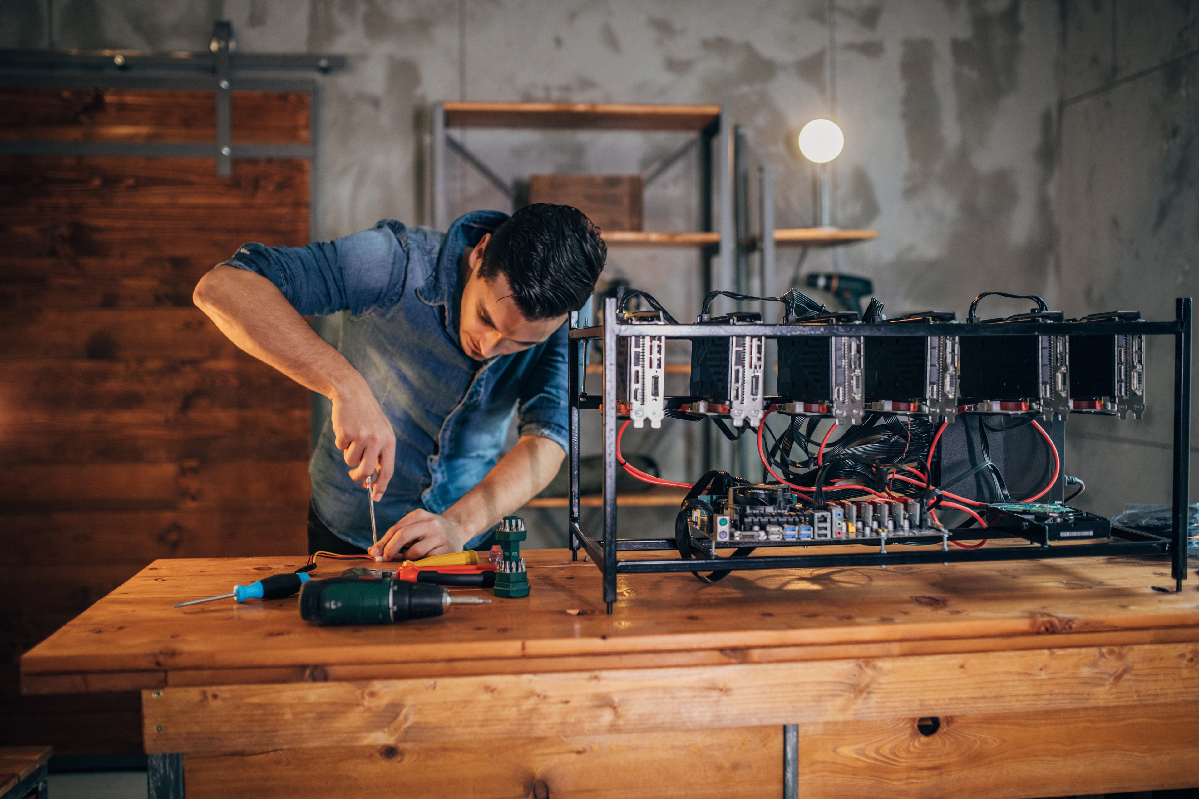 A person with tools setting up a Bitcoin mining rig. 