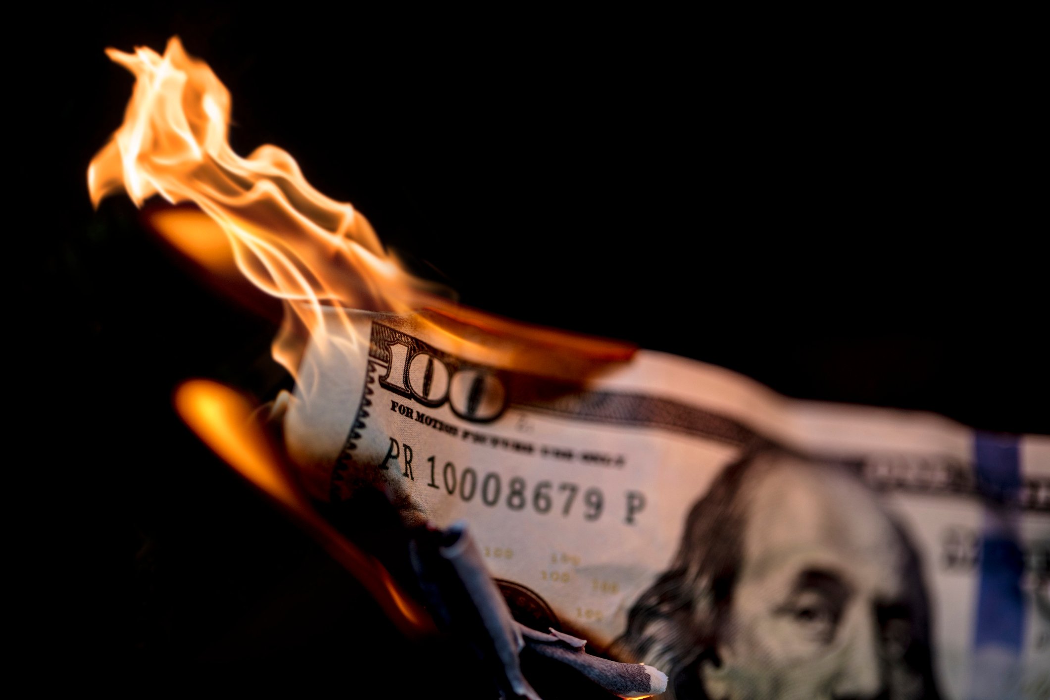 A one-hundred dollar bill is on fire.