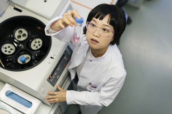 Scientist looking up at a sample tube in a lab.