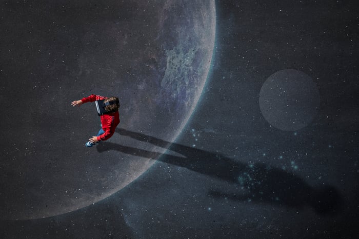 A person wearing a virtual reality headset walking on an image of the moon.