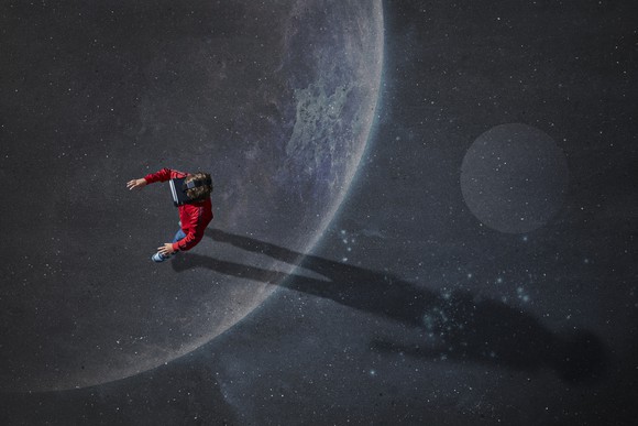 A person wearing a virtual reality headset walking on an image of the moon.