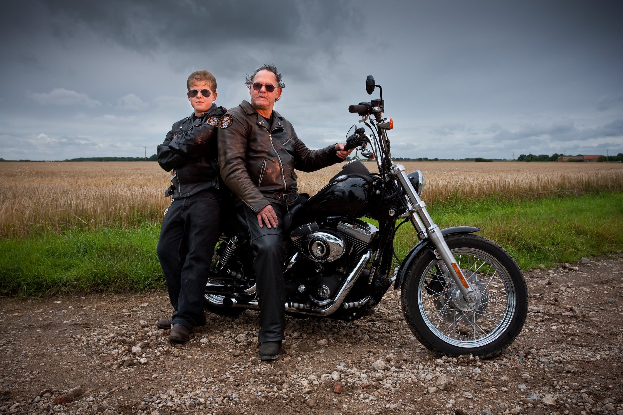 Parent and offspring with a large Harley-type motorcycle, representing continuation of the motorcycling trend across generations.