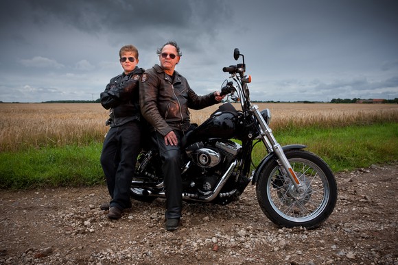 Parent and offspring with a large Harley-type motorcycle, representing continuation of the motorcycling trend across generations.