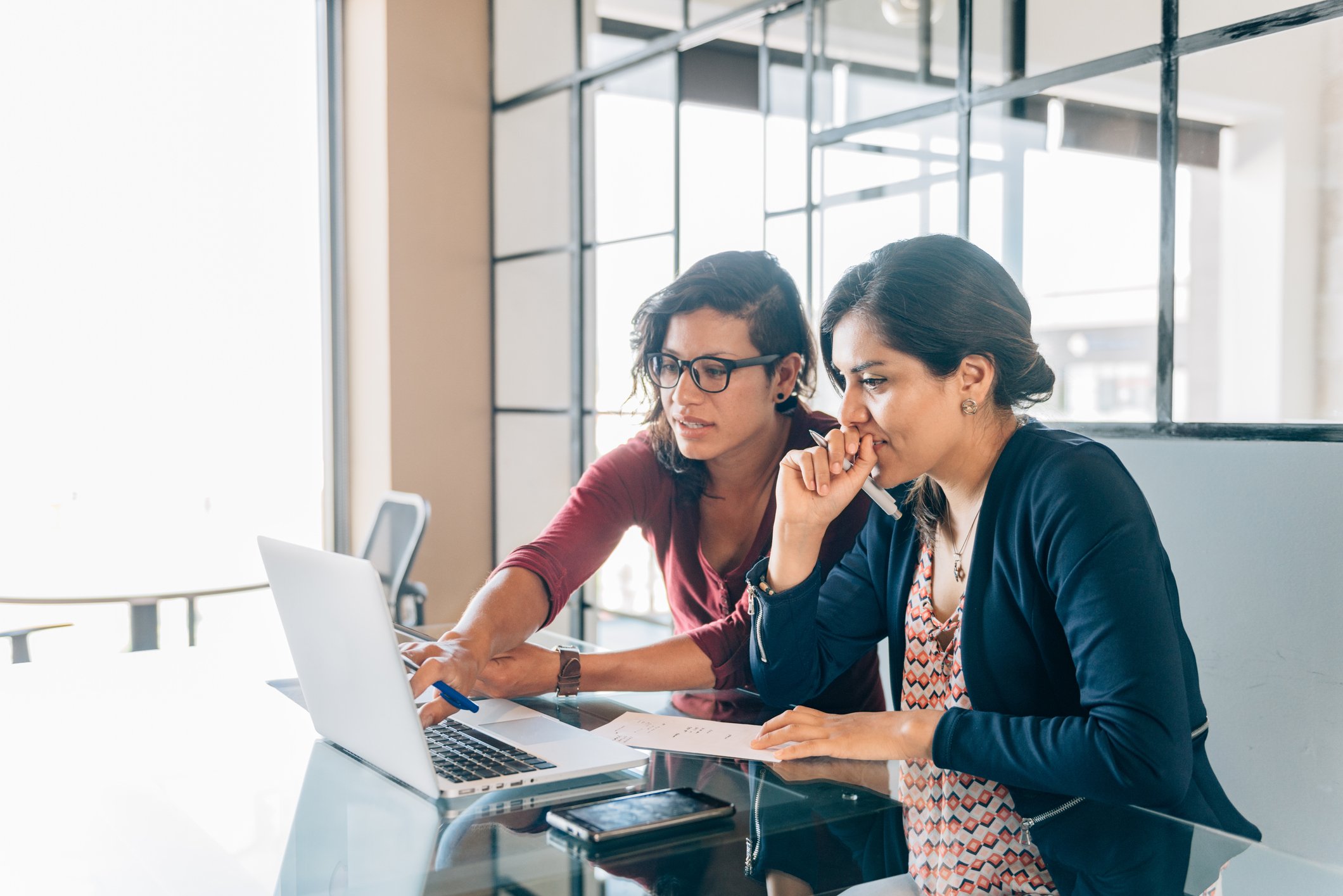 Two people study something on a computer in a modern office.