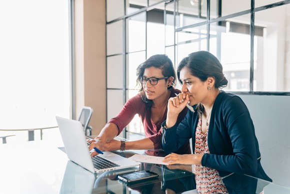 Two people study something on a computer in a modern office.