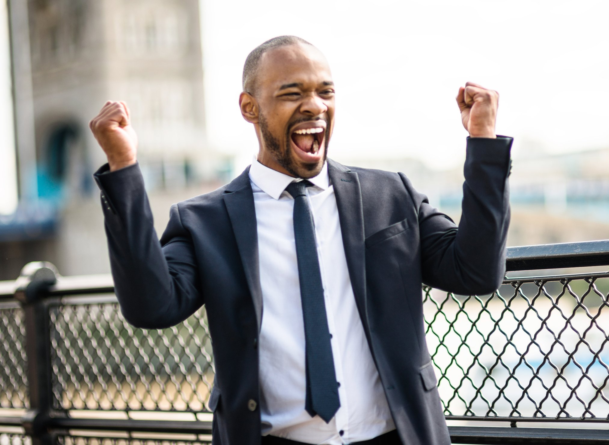 A man in a suit celebrates on a city street. 