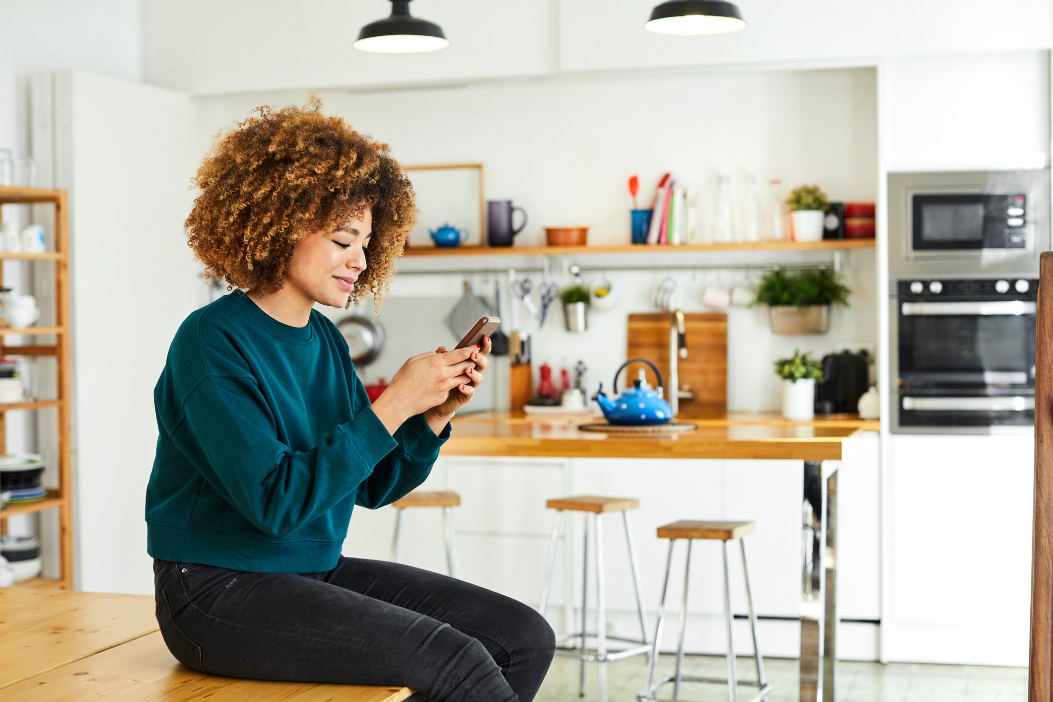 A person looking at their phone in a kitchen.