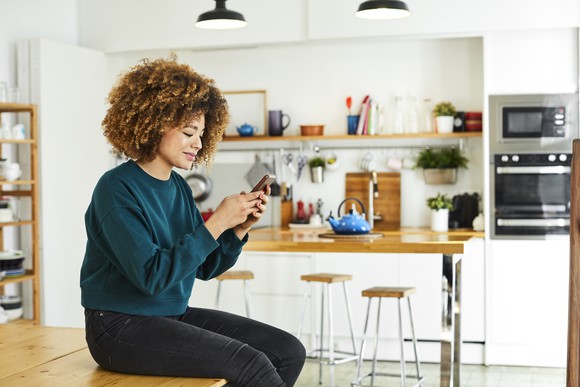 A person looking at their phone in a kitchen.