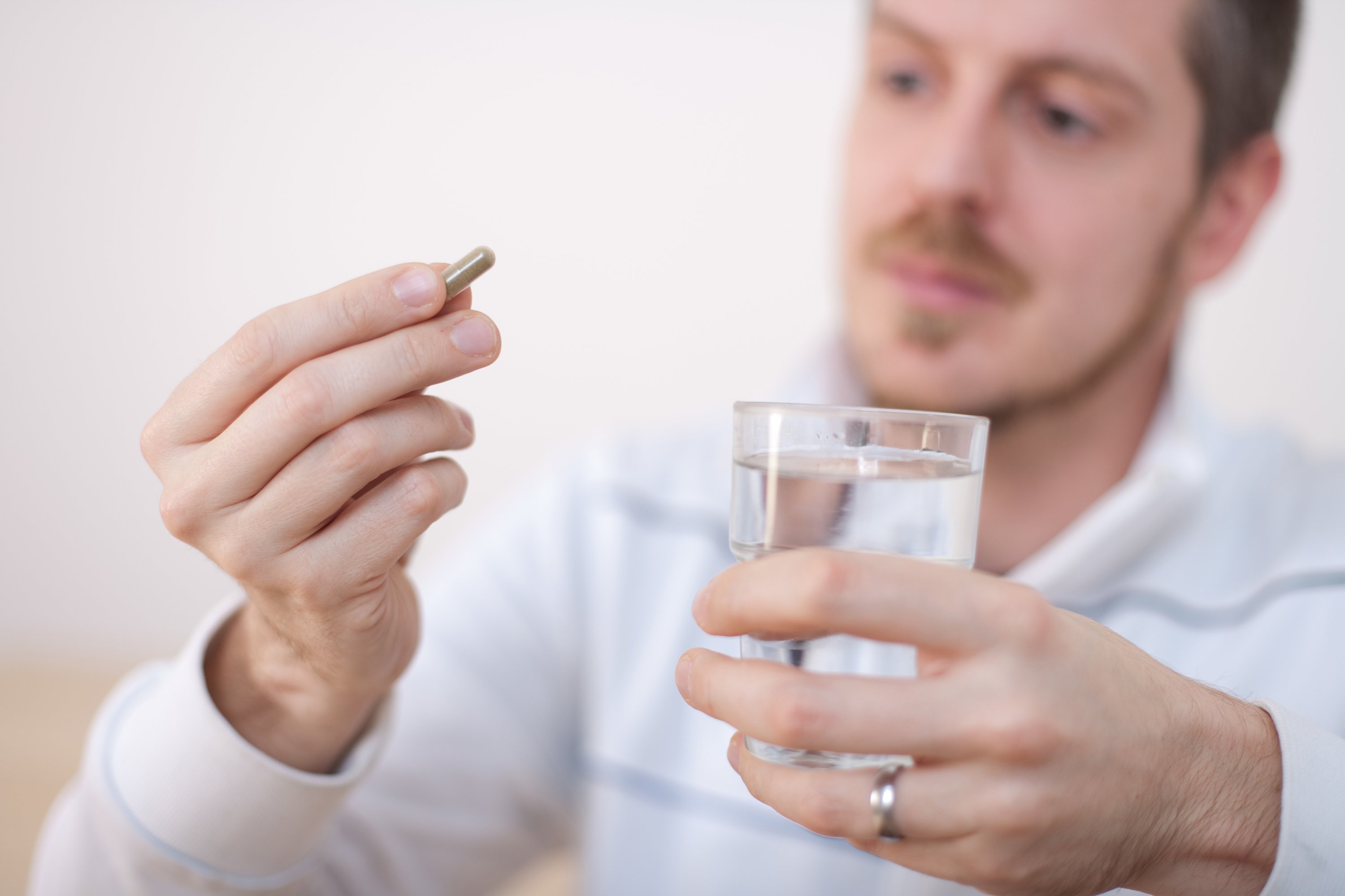 A person holding a pill and a glass of water.
