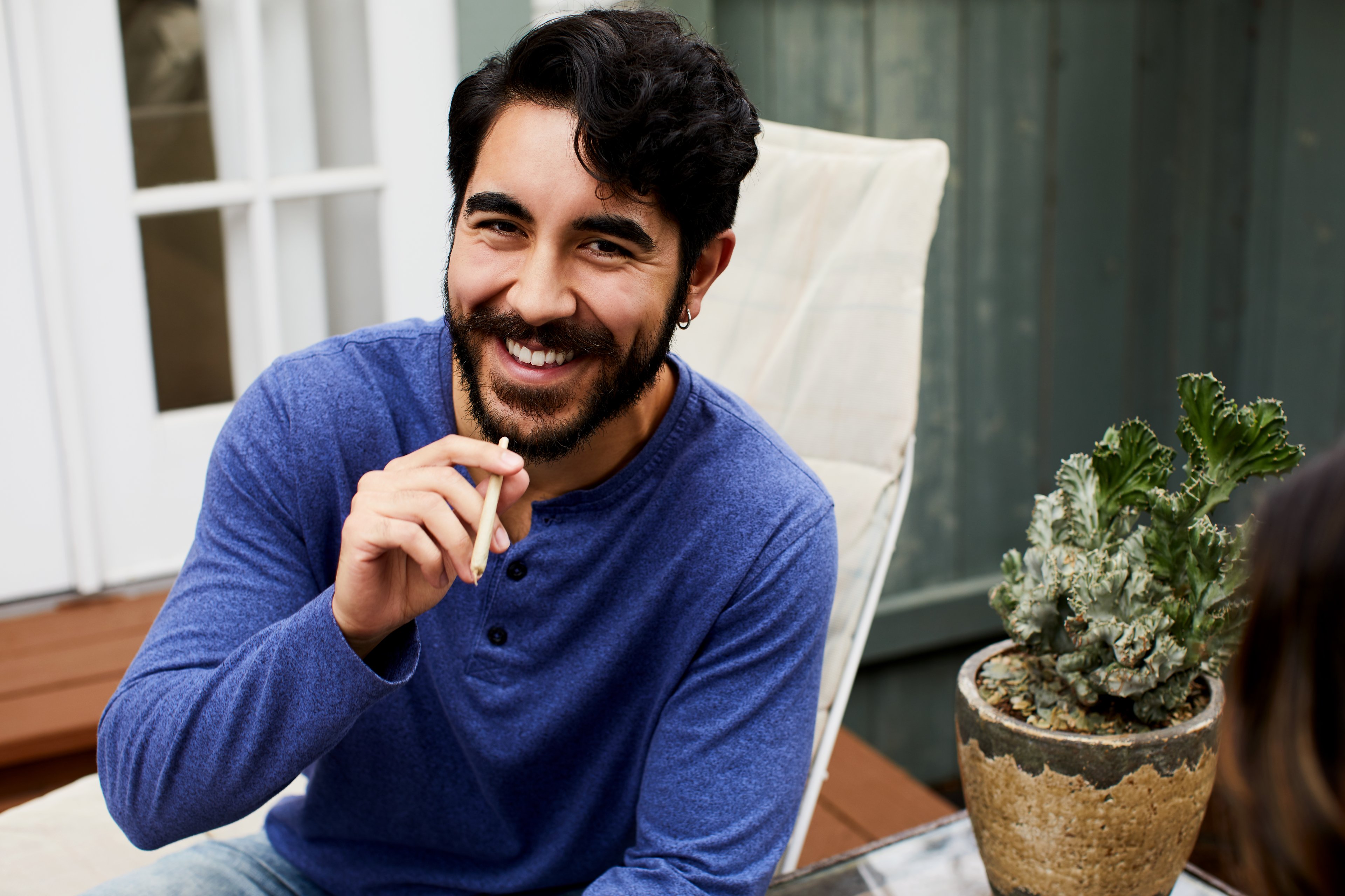 A person sits outside holding a marijuana joint.