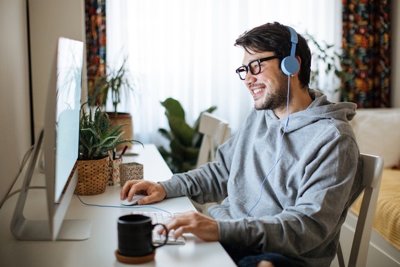 A man plays a computer game while wearing a headset.
