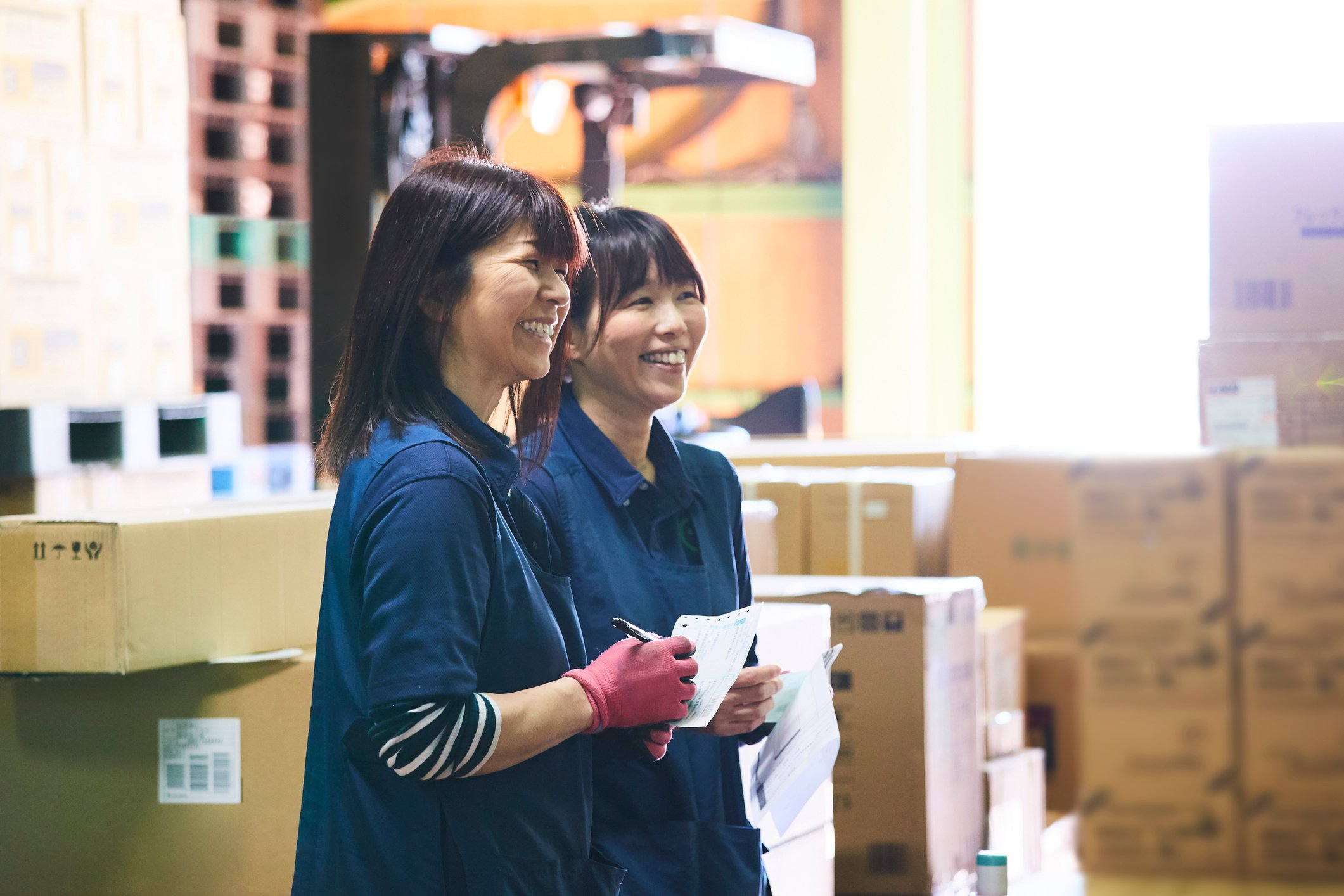 Two workers smiling in a warehouse. 